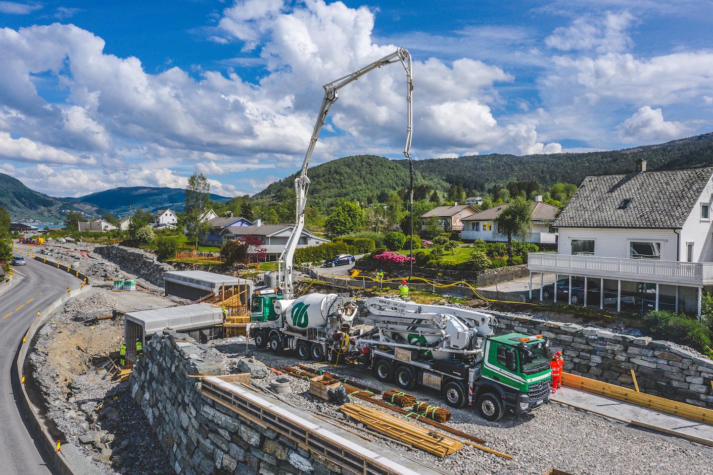 To betongbiler med pumpe leverer betong i Ølensvåg med vakkert landskap i bakgrunnen